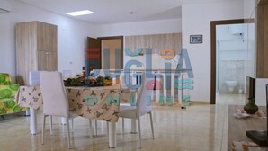 A modern kitchen with a dining area. There is a table with chairs, a cabinet, and a sink.