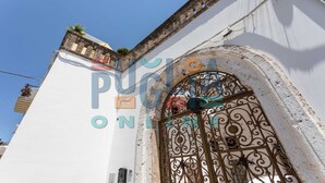Ein weißes Gebäude mit schmiedeeisernem Ziergitter und einem Balkon mit Blumen.