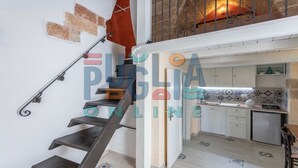 Eine Treppe führt zu einem Schlafzimmer auf dem Dachboden, mit Blick auf eine Küche und einen Balkon.