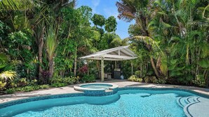 A swimming pool with a circular design, surrounded by lush greenery and a covered seating area.