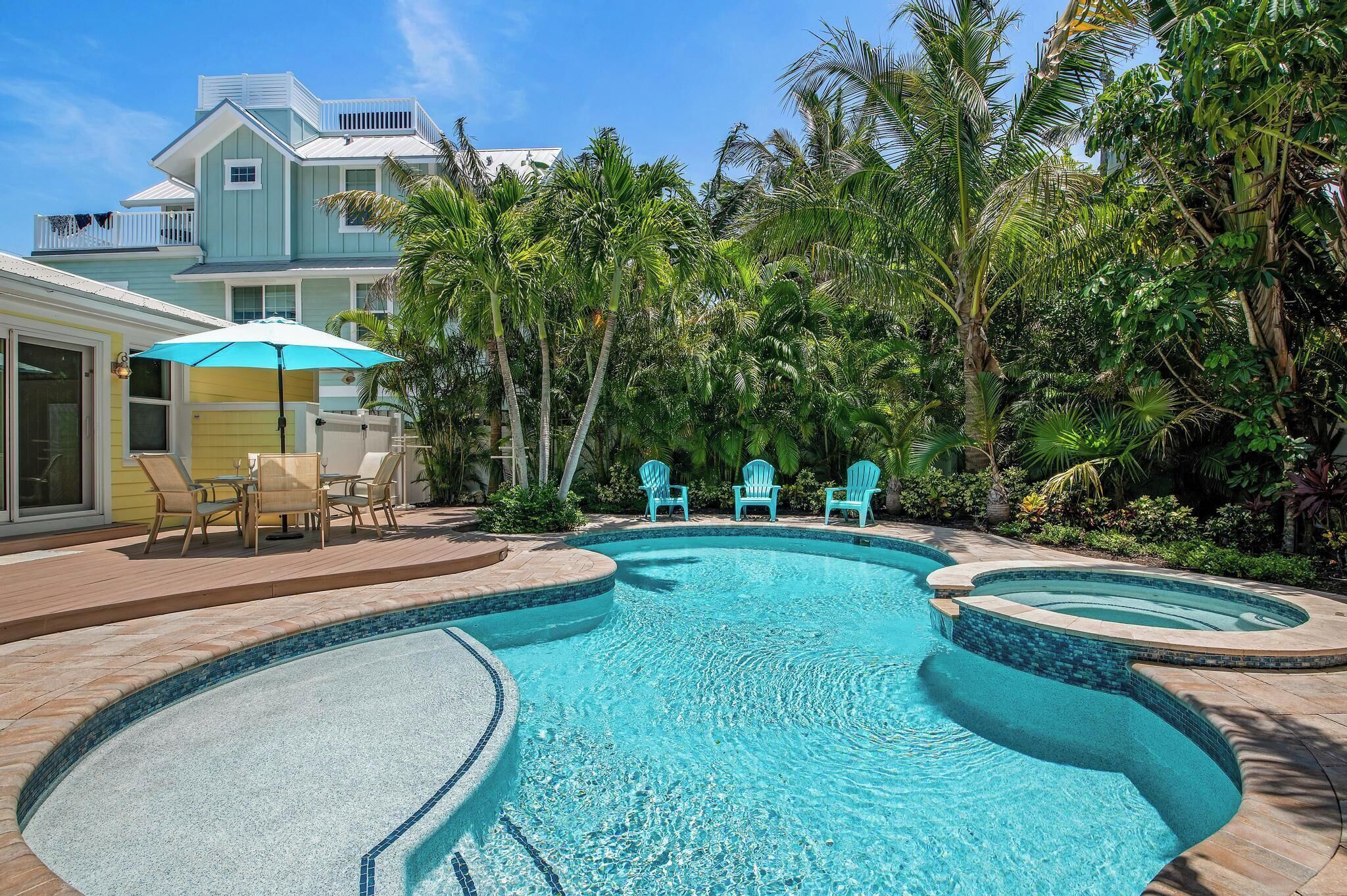 A swimming pool with a curved design, surrounded by palm trees and a deck with chairs.