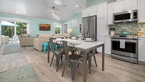 A modern kitchen with white cabinets, stainless steel appliances, and a dining area with a table and chairs.