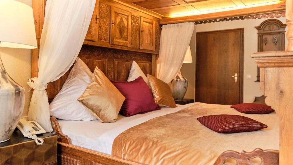 A traditional wooden bed with a canopy, a bedside telephone, and a nightstand.
