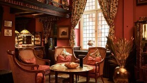 A cozy room with wicker chairs, a round table, and a large window with curtains. - Hotel Van Bebber (Xanten)