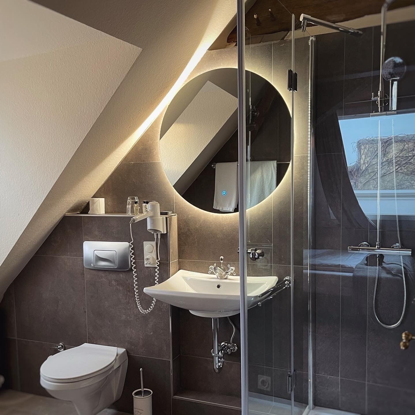 Een moderne badkamer met een douchecabine van glas, een wastafel en een toilet.