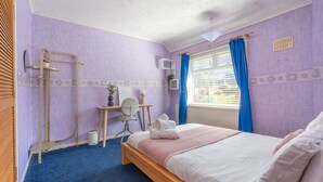 Un dormitorio con cama, escritorio, silla y ventana con cortinas.