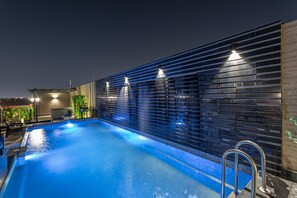 Una piscina interior de diseño moderno, con una pared de azulejos oscuros y agua azul.