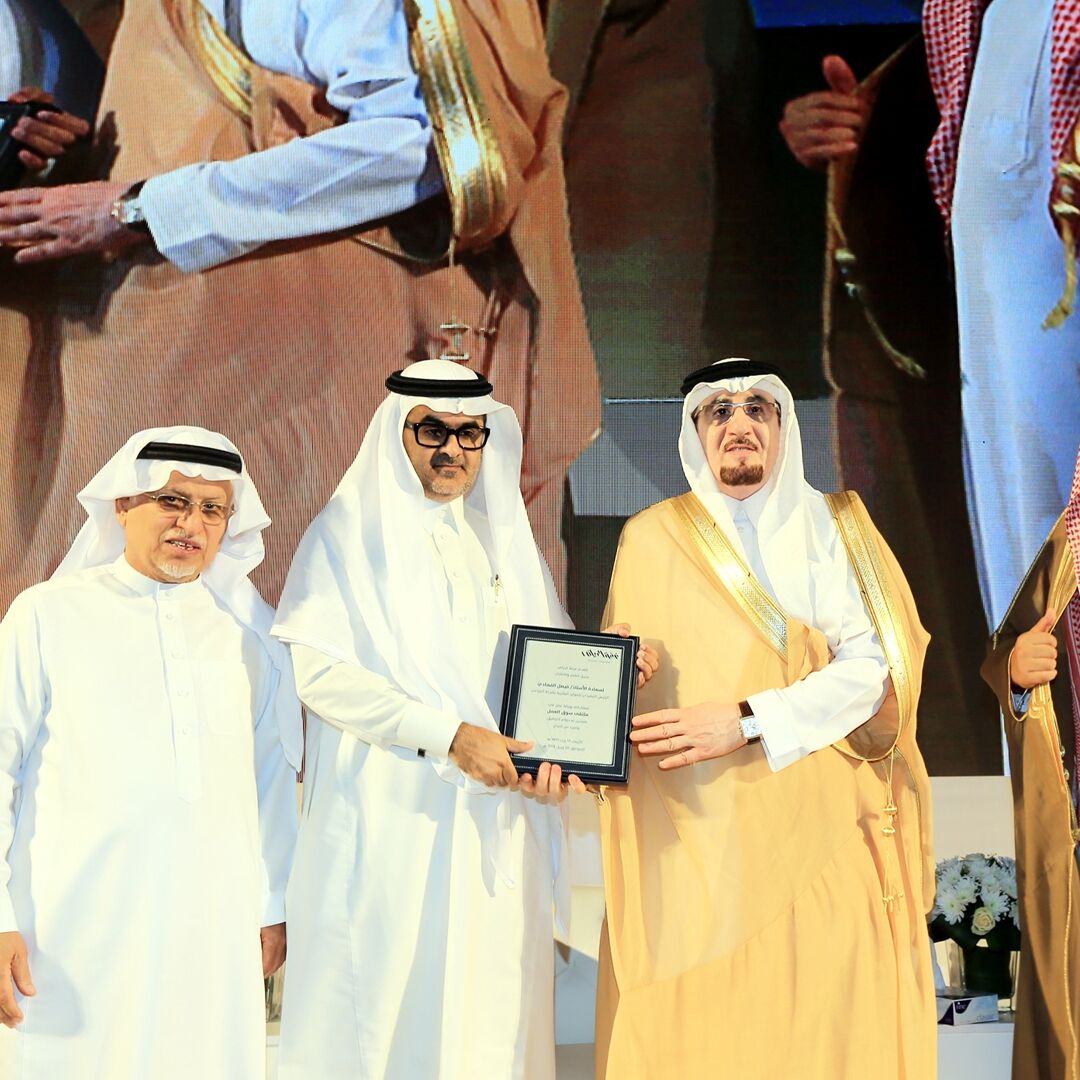 Three individuals in traditional attire holding a framed certificate.