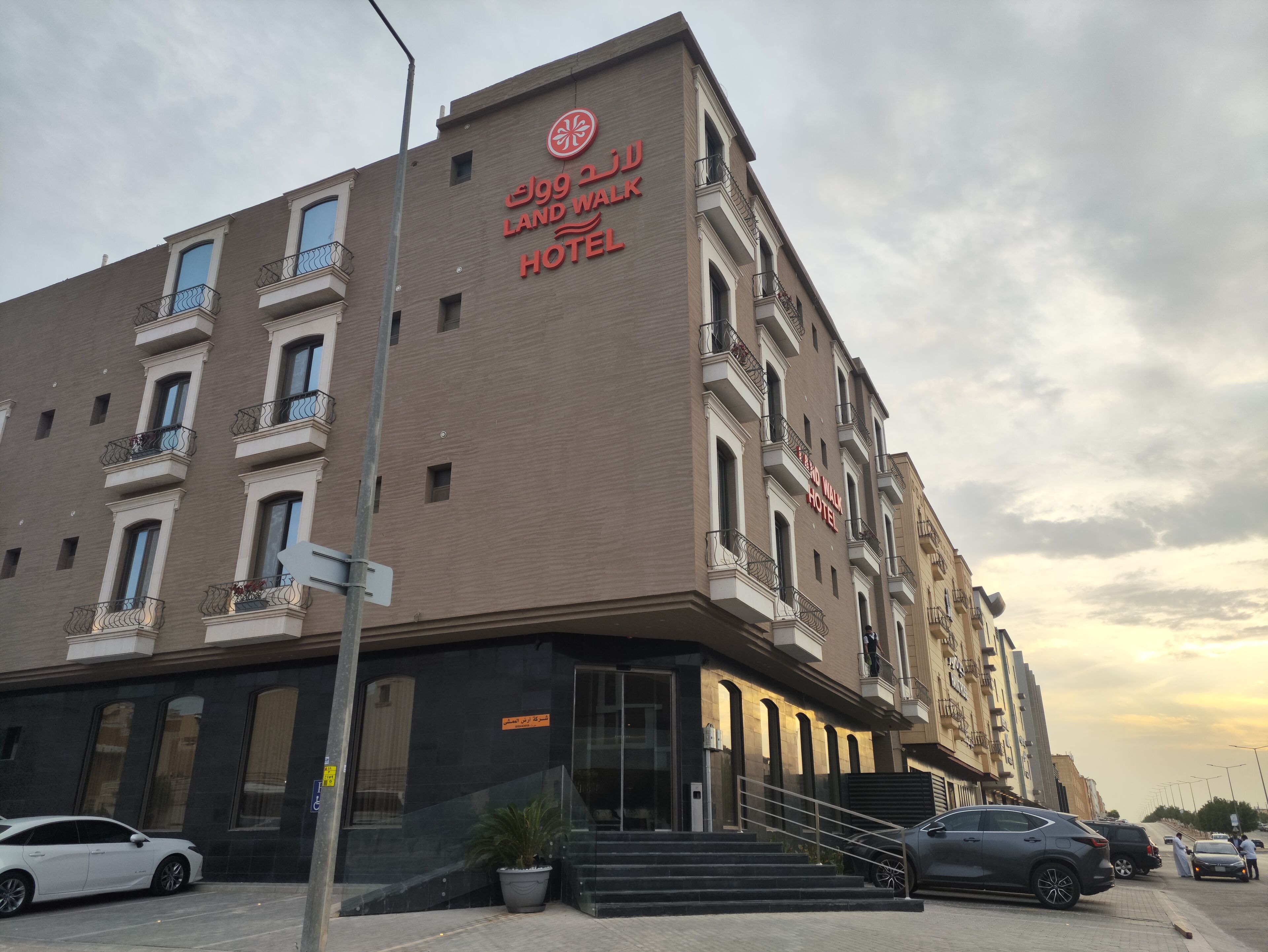 Een hotel met een opvallend bord, meerdere balkons en een moderne ingang.