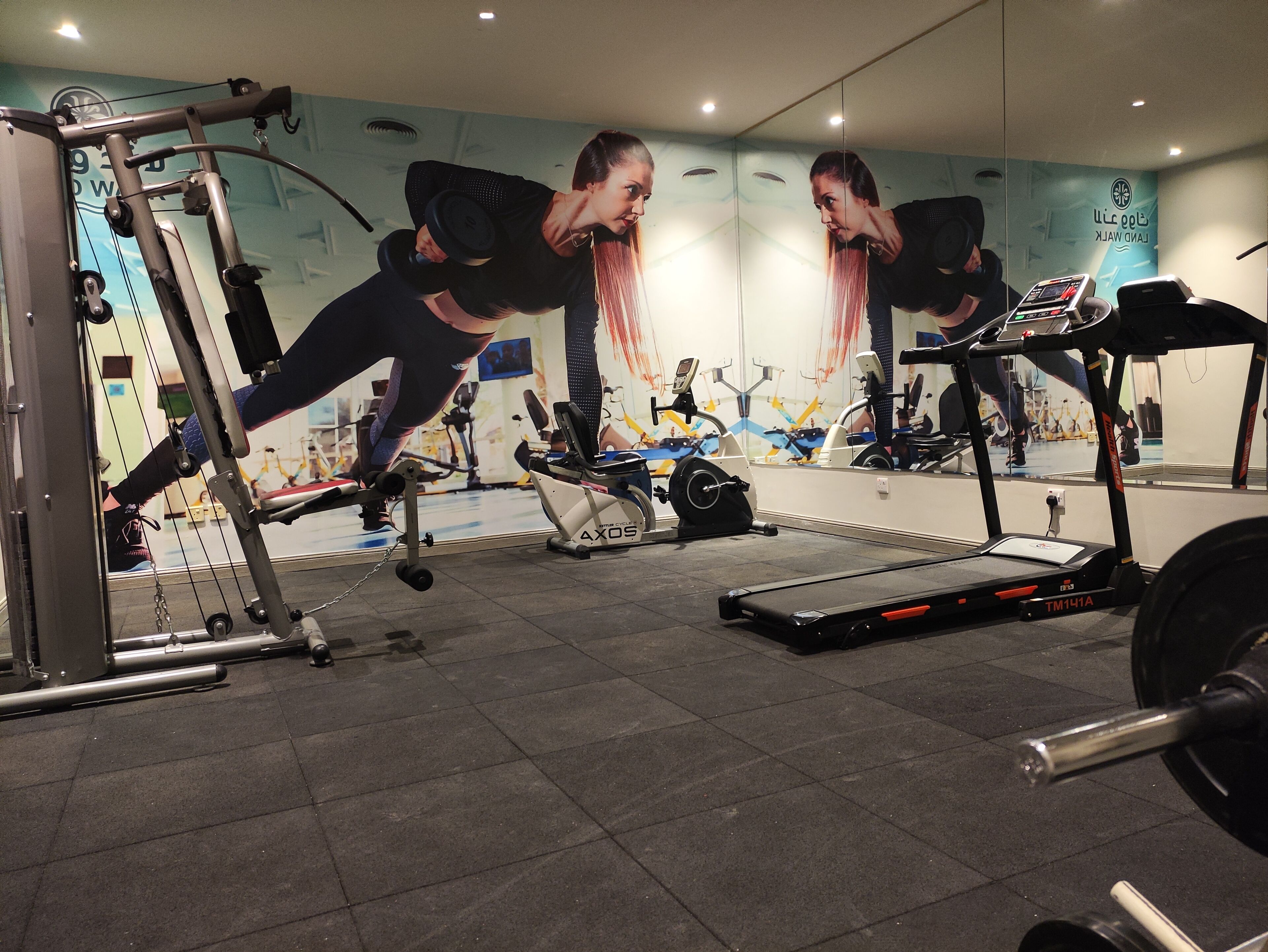 A gym with exercise equipment, a mirrored wall, and a treadmill.