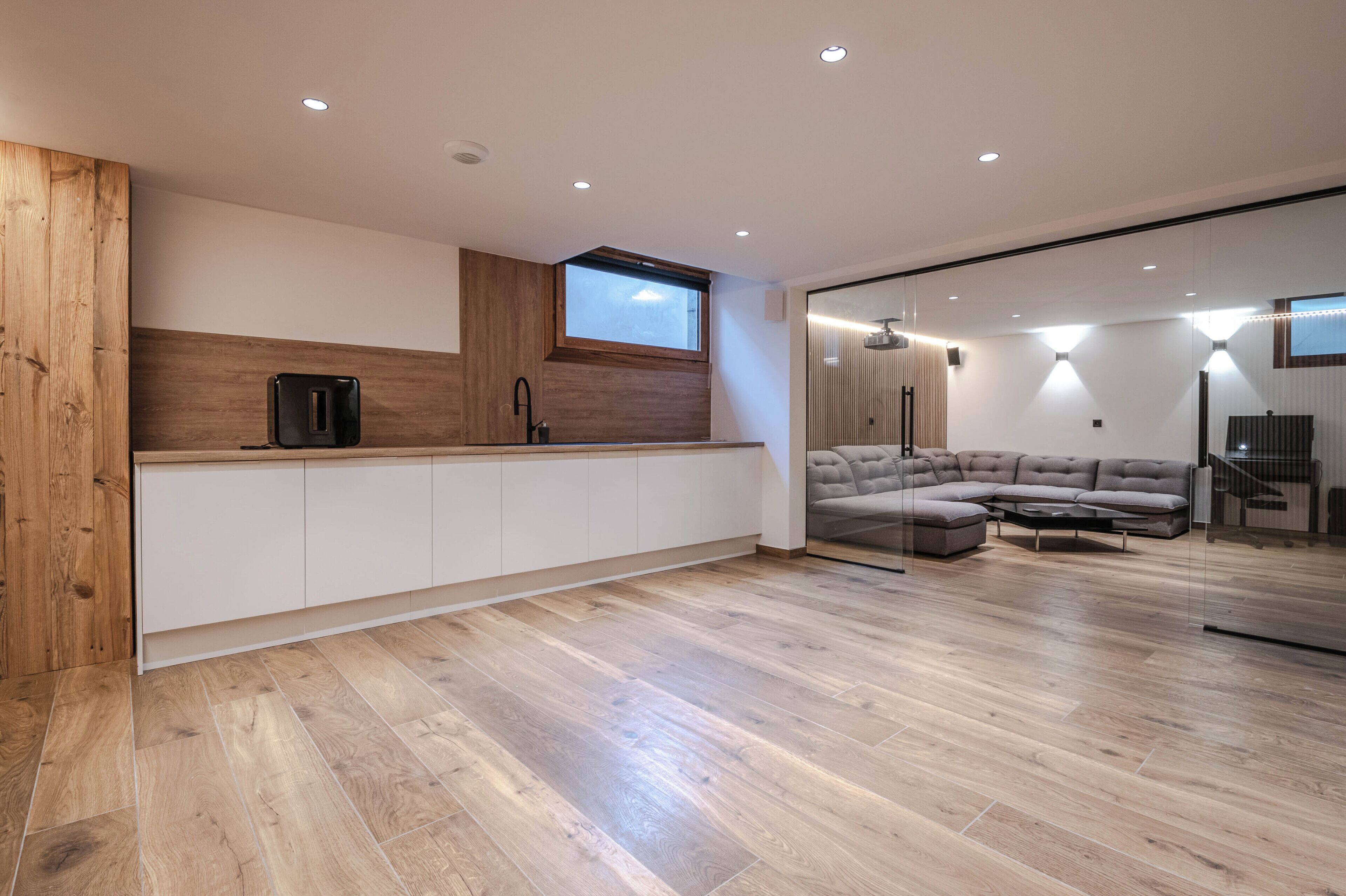 A modern kitchen with wooden accents, a built-in oven, and a large window.