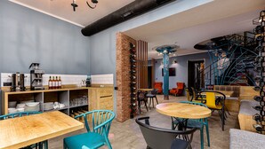 Une cuisine moderne avec des meubles en bois, un mur en briques et un coin repas agrémenté de chaises turquoise et d’une table ronde en bois.