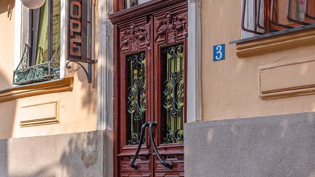 L’entrée d’un hôtel, avec une porte double en bois, une enseigne au-dessus de la porte et le chiffre « 3 » peint sur le mur.
