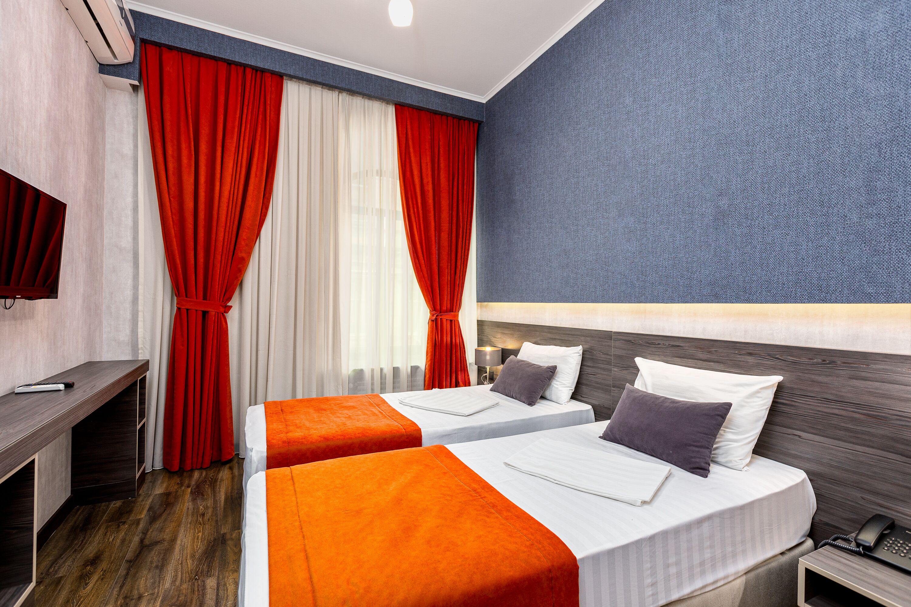 A hotel room with two beds, a desk, and a TV.