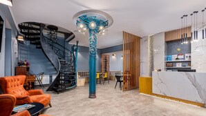 Un hall d’entrée moderne avec un escalier en colimaçon, un comptoir d’accueil et des espaces aménagés pour s’asseoir.