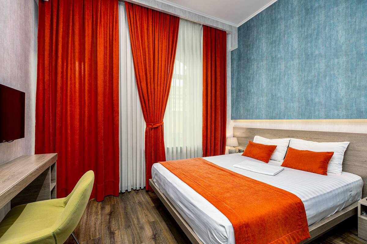 A hotel room with a bed, a desk, and a chair.