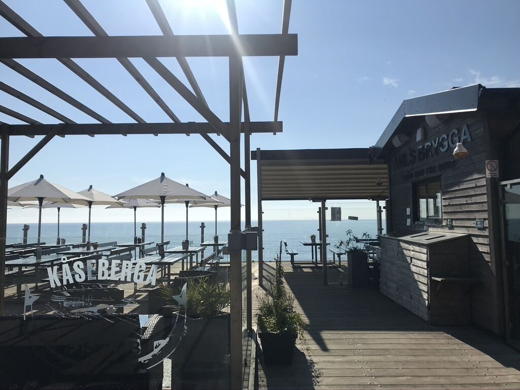 En träveranda med utomhusmöbler och utsikt över havet.