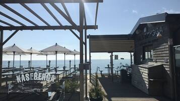 En träveranda med utomhusmöbler och utsikt över havet.