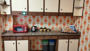 Una cocina con un tostador rojo, una cafetera y frascos de almacenamiento sobre la encimera.