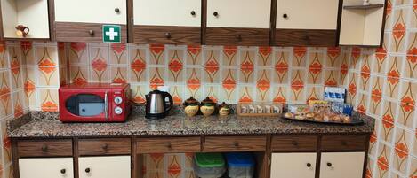 Una cocina con un tostador rojo, una cafetera y frascos de almacenamiento sobre la encimera.