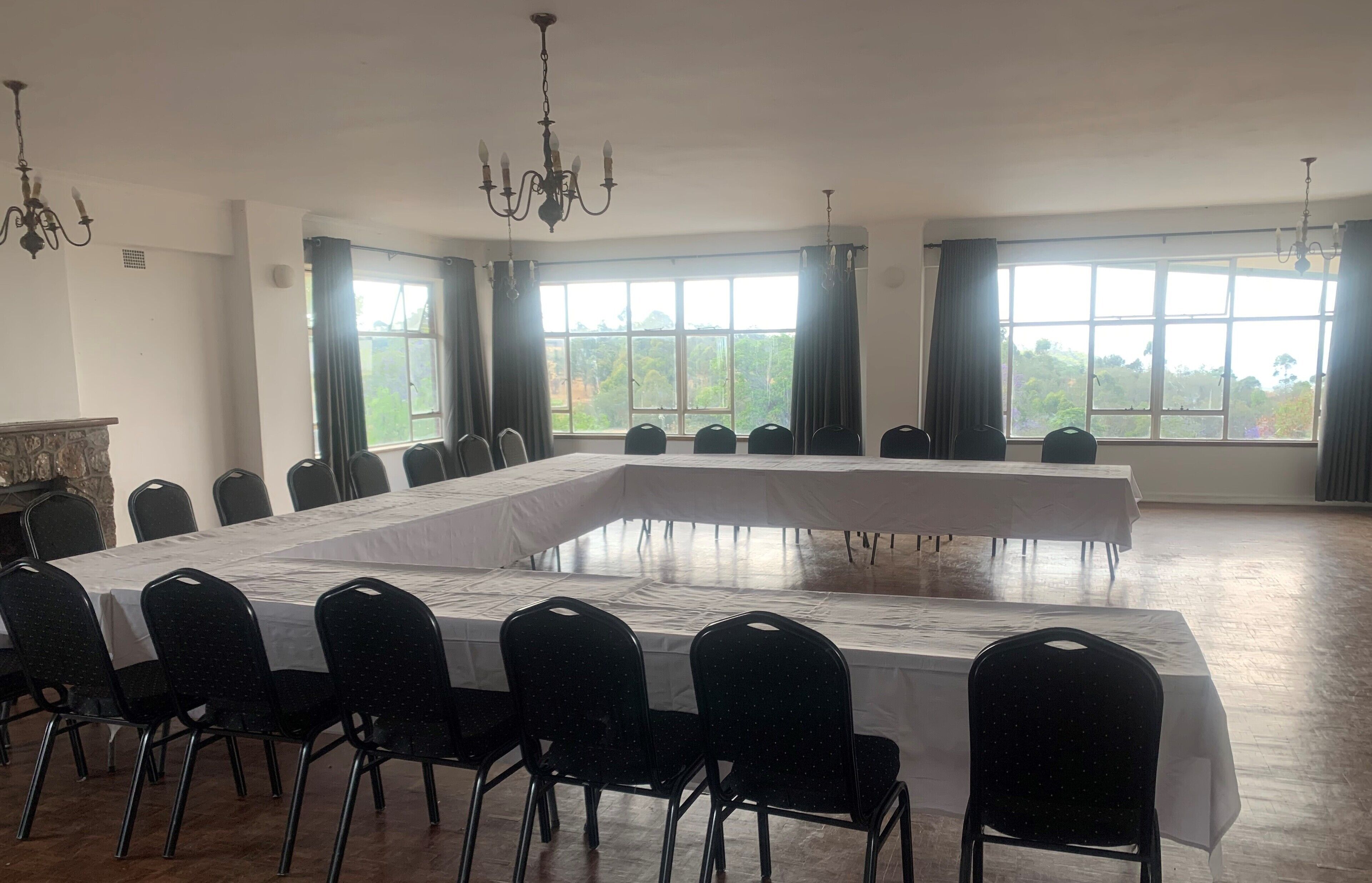Une salle de conférence dotée d’une longue table, de chaises noires et de grandes fenêtres équipées de rideaux.