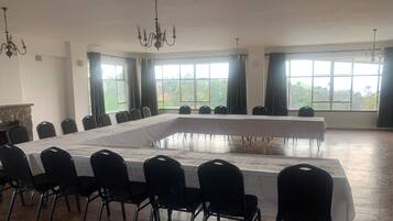 Une salle de conférence dotée d’une longue table, de chaises noires et de grandes fenêtres équipées de rideaux.