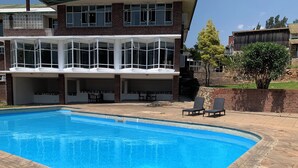 A two-story house with a swimming pool, outdoor seating, and a brick exterior. - Brondesbury Park Hotel (Juliasdale)