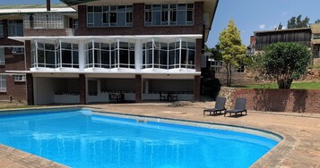 Una casa de dos pisos con piscina, mobiliario exterior y fachada de ladrillo.