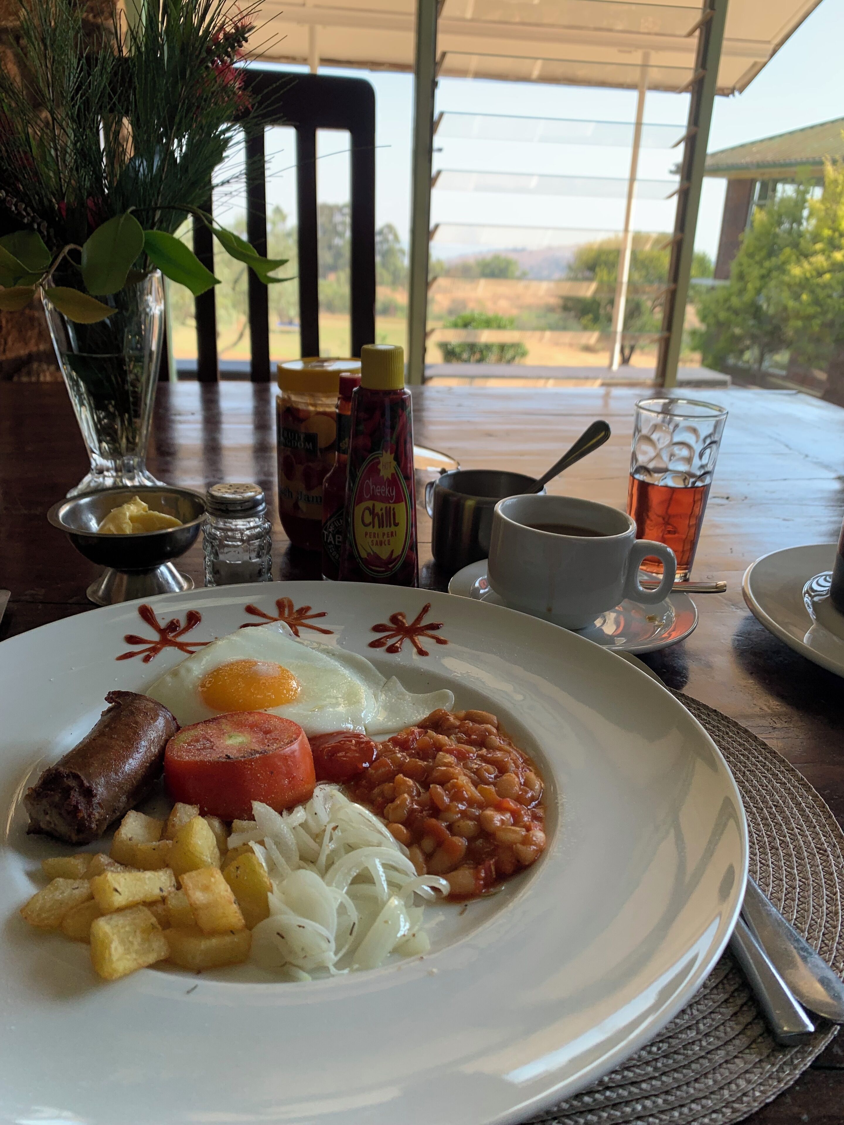 A breakfast plate with eggs, sausages, tomatoes, beans, and potatoes.