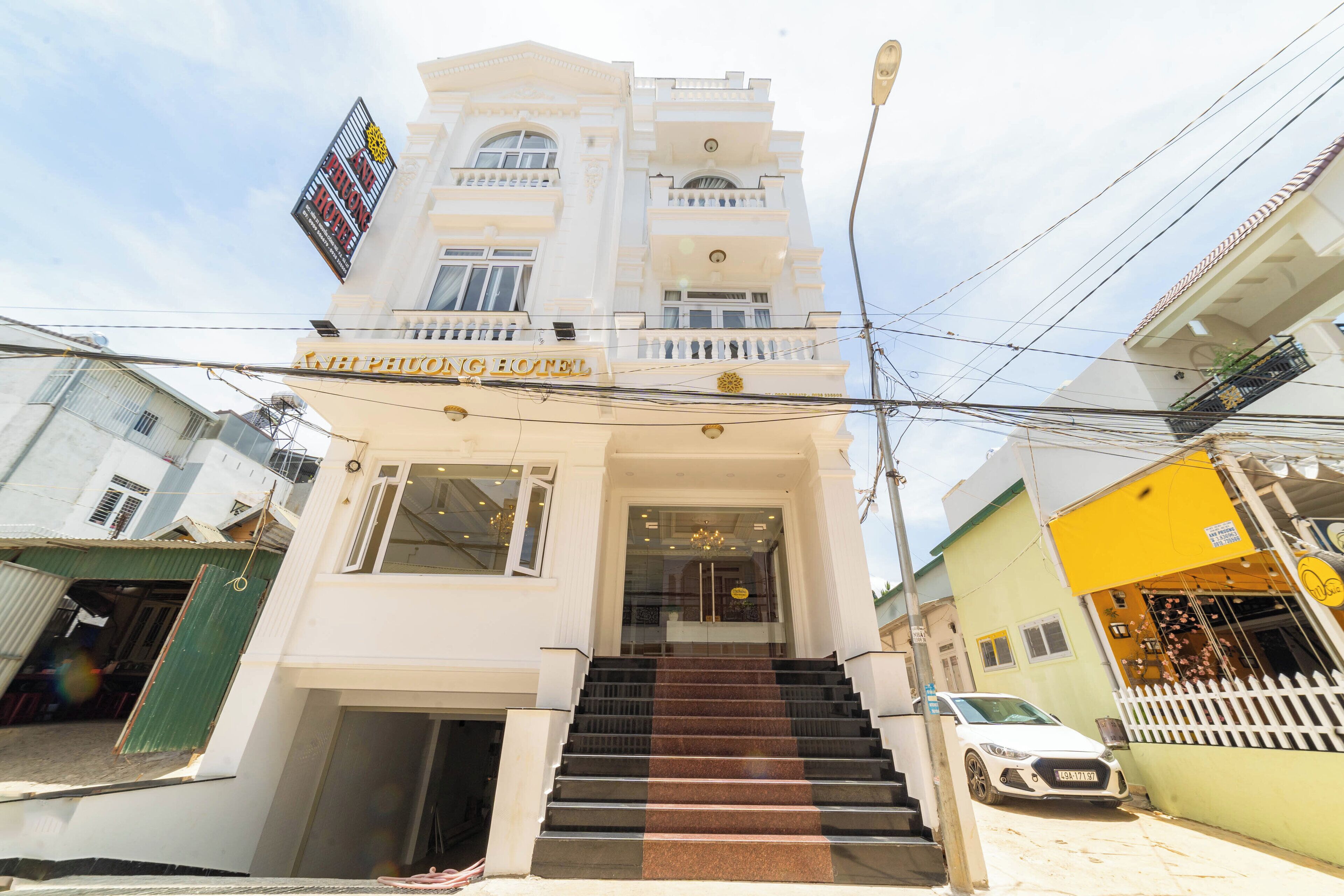 A hotel entrance with a staircase leading to the lobby, surrounded by other buildings.