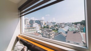 Une chambre avec une grande fenêtre donnant sur le paysage urbain.