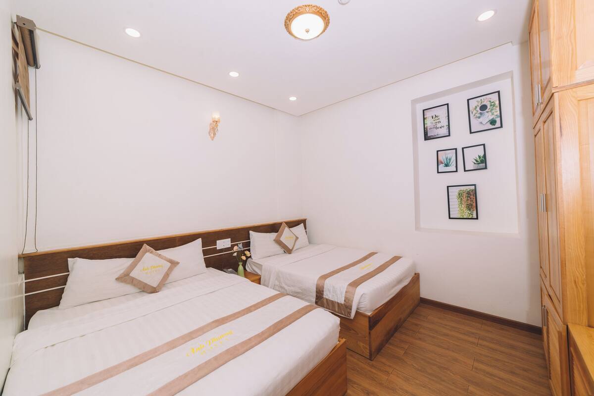 Een hotelkamer met twee bedden, houten hoofdborden, een houten garderobe en een muur met ingekaderde botanische prints.