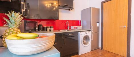 A compact kitchen with black cabinets, a washing machine, and a microwave.