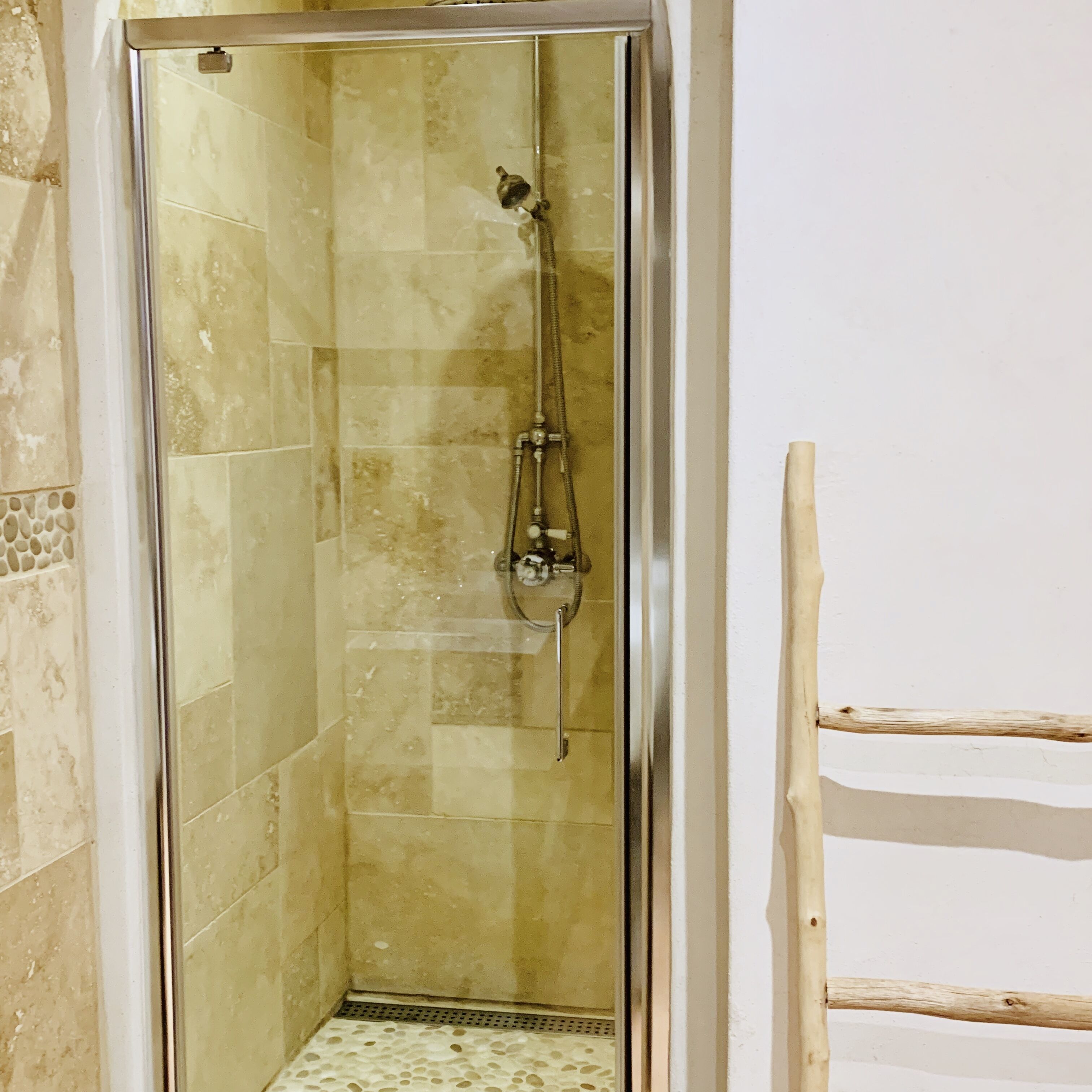 A glass-enclosed shower stall with a tiled floor and a showerhead.