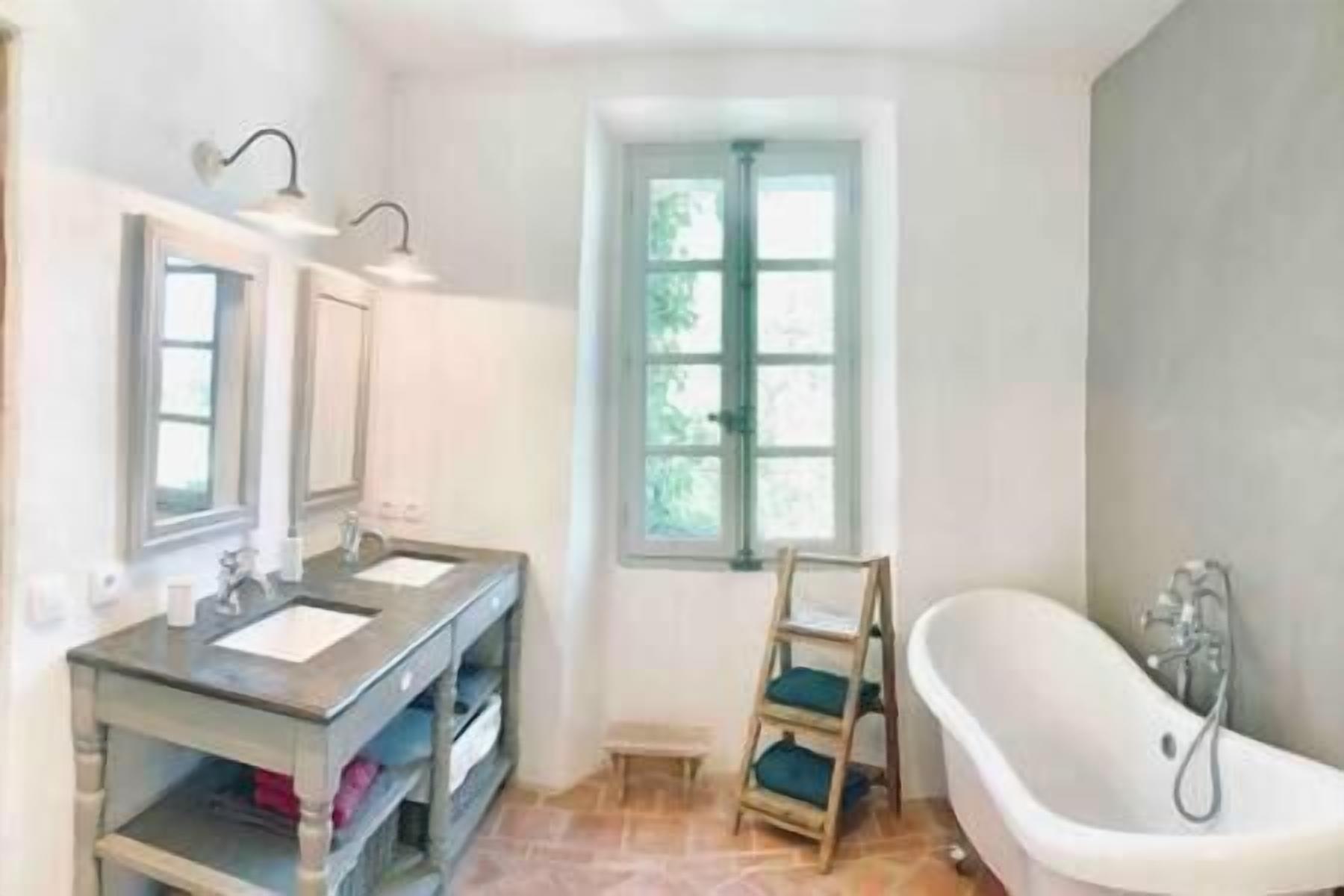 A bathroom with a vanity, a bathtub, and a window.
