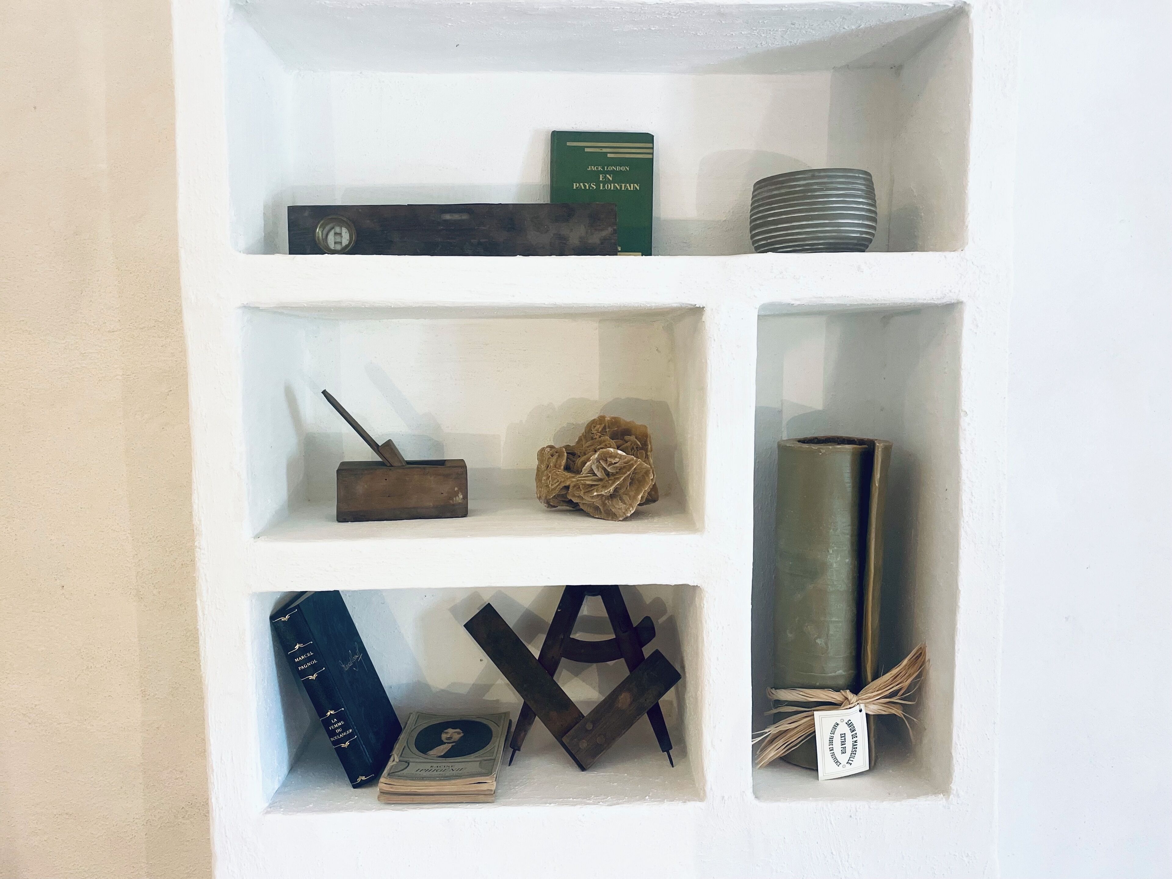 Una estantería con diversos objetos, incluyendo libros, una caja verde y adornos.