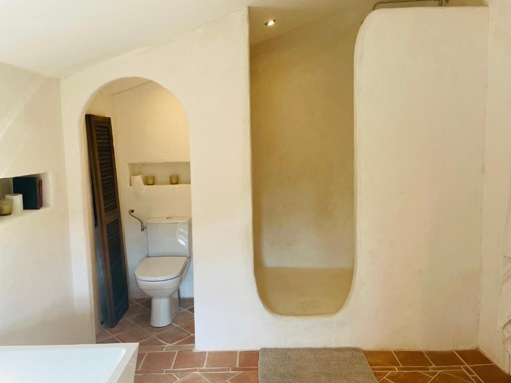 Et badeværelse med toilet, badekar og bruseniche.