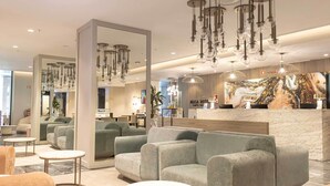 Een moderne hotel lobby met comfortabele zithoeken, een marmeren receptiebalie en moderne verlichtingsarmaturen.