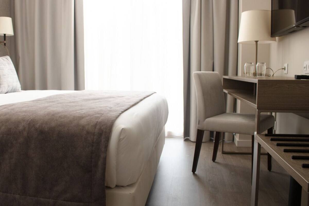 Una habitación de hotel moderna con una cama grande, un escritorio con lámpara y televisión.