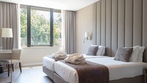 Een hotelkamer met een groot bed, twee nachtkastjes, een bureau en een stoel.