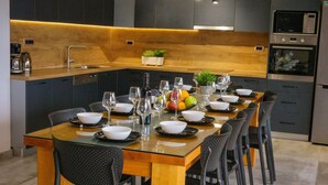 A modern kitchen with a central island, dark cabinetry, and a dining area with a glass table and black chairs.