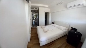 A modern bedroom with a bed, a suitcase, and a view of a balcony. - 13 Palazzaccio Rock - Studio (Tavarnuzze)