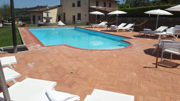 A swimming pool with lounge chairs and umbrellas, surrounded by a brick patio and a building in the background. - 13 Palazzaccio Rock - Studio (Tavarnuzze)