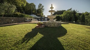 A stone fountain with a tiered design, surrounded by a well-maintained lawn and a stone wall. - 13 Palazzaccio Rock - Studio (Tavarnuzze)