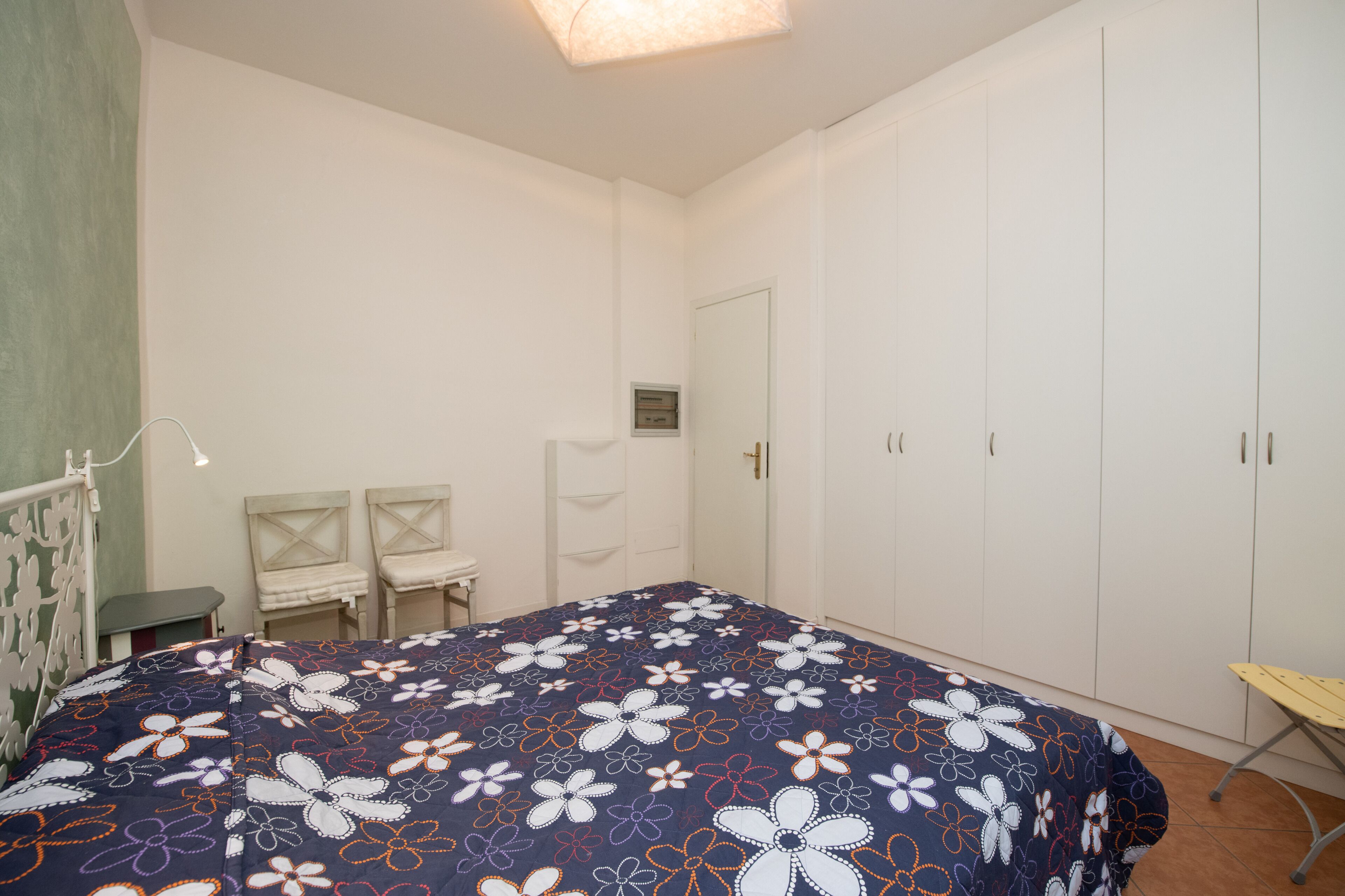 Ein Schlafzimmer mit einem Bett, zwei Stühlen, einem Schreibtisch und einem Kleiderschrank.