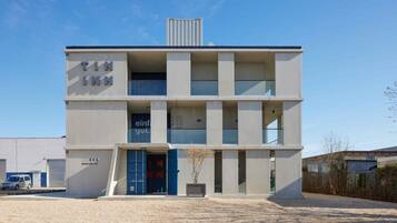 Un edificio moderno con techo plano, entrada azul y un letrero que dice 'TIN INN'.