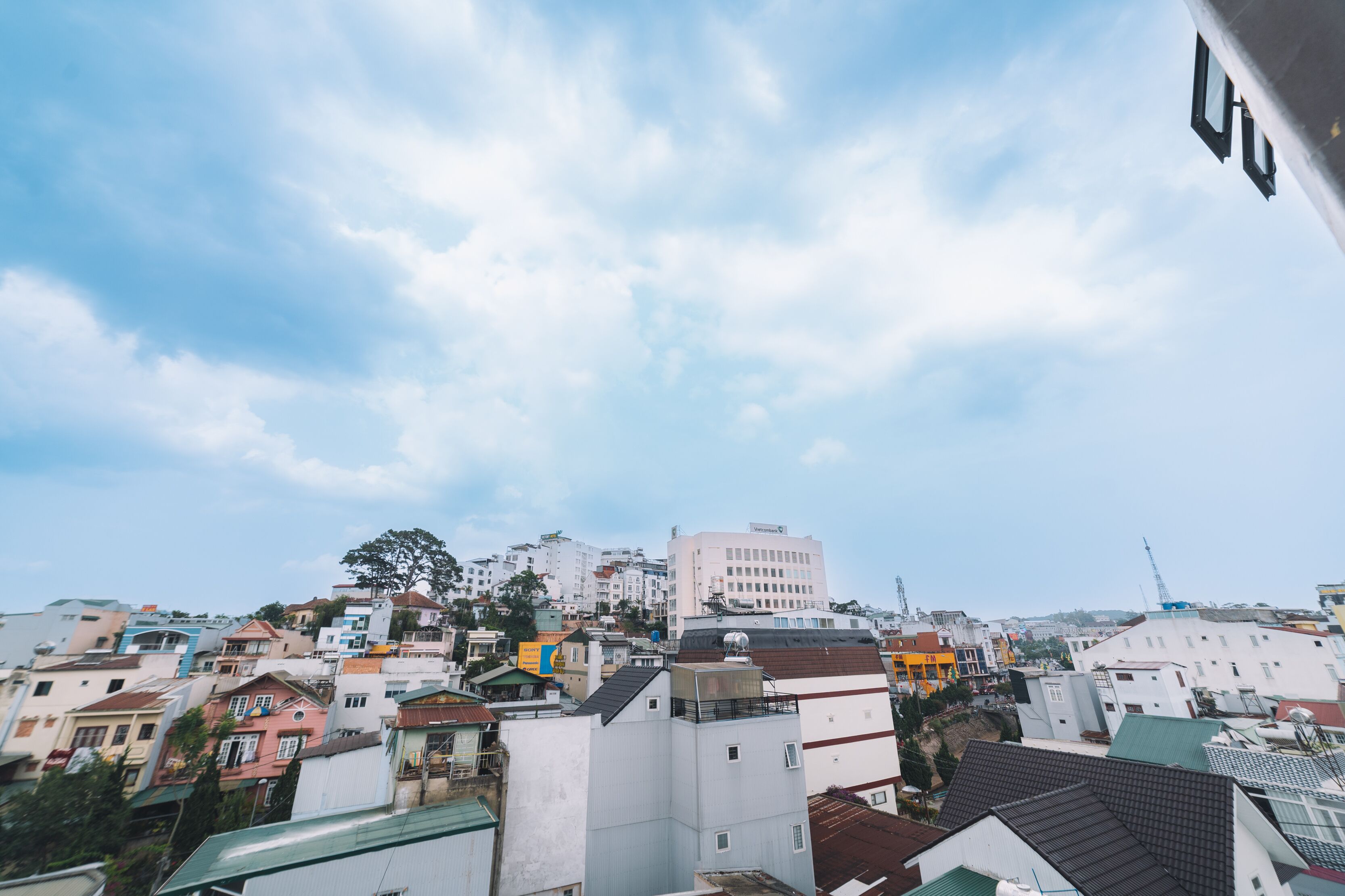 A cityscape with various buildings, including a prominent white building with a flat roof and a large antenna.