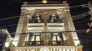 Un hotel con un cartel llamativo que dice "HANA HOTEL" y un balcón con barandilla.
