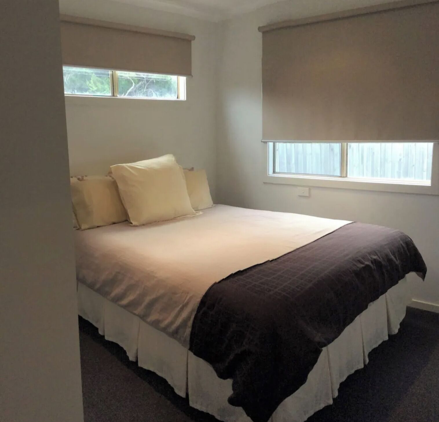 A bedroom with a bed, two windows, and a ceiling fan.