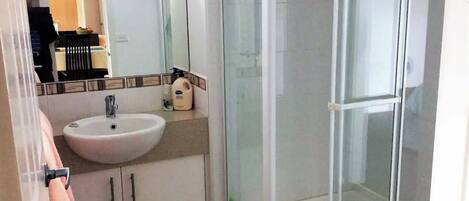 A bathroom with a white sink, a mirror, and a glass-enclosed shower.
